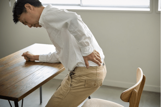 A man suffers from back pain while he's sitting